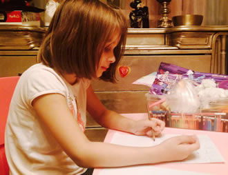 Девочка пишет письмо Деду Морозу с пожеланиями