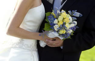 Молодые муж и жена держат свадебный букет